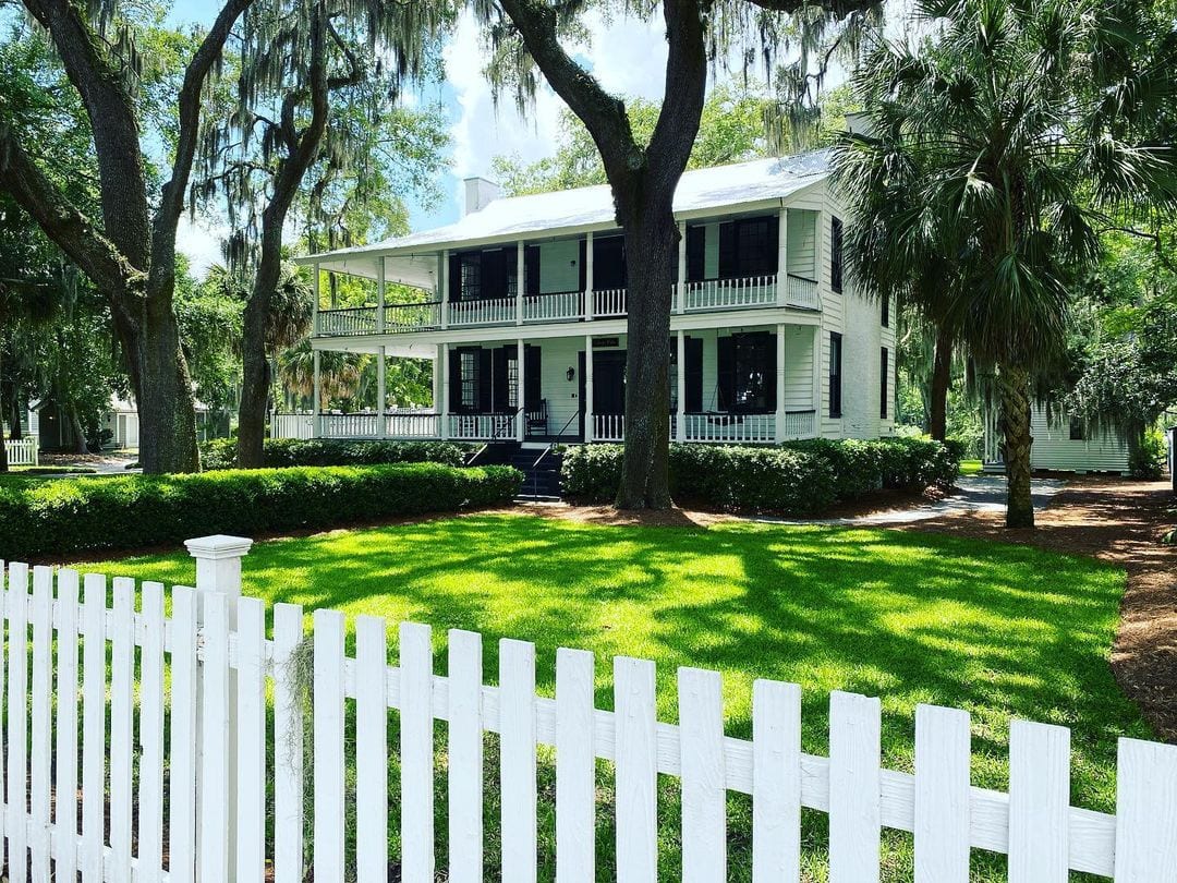 White picket fence with big country house in the background